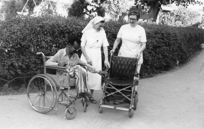 250334 Zuster Paschasia Brom (vermoedelijk rechts) bij de aanbieding van een nieuwe rolstoel, voor een ziekenhuis in Pakistan