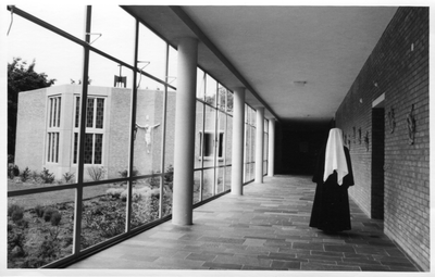 274195 Een zuster loop door de gang naar de kapel van het moederhuis te Roosendaal