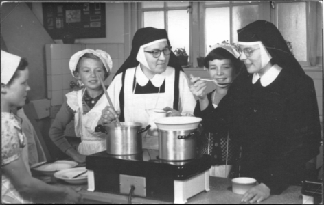 252059 De zusters Brigida Boemaars en Ediltrude Cualenaers geven huishoudles in de keuken van de V.G.L.O. school te Alphen