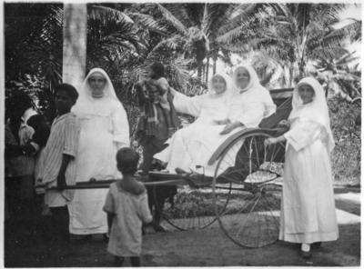 252295 De zusters Anselmo, Alphonsine, Rudolphine en Theobalda (vlnr) in en naast een riksja, Indonesië