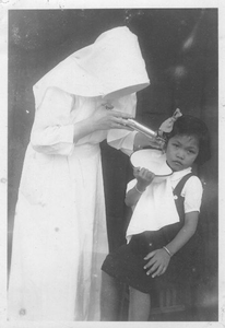 178215 Zuster Immaculata bezig met het uitspuiten van een oor (Nederlands-Indië)