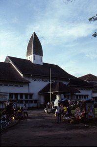 178337 Ziekenhuis Sint Elisabet te Medan met op de voorgrond kleine kraampjes met fruit en andere waren (Indonesië)