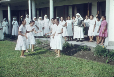 178353 De zusters dansen op het accordeonspel van een medezuster te Deli Tua (Indonesië)