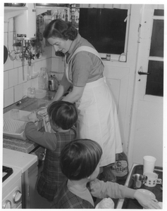 202096 Zuster Dorothea als gezinsverzorgster bezig met de afwas