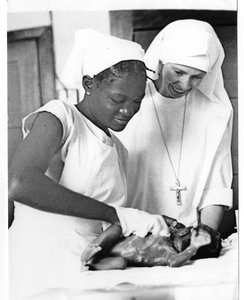 206146 Zuster Clementine Damen geeft kraamles aan een leerling te Pendjua (Congo)