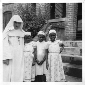116173 Zuster Alfonso Marie en drie weesmeisjes op de dag van hun Eerste Communie voor het huis van de zusters in ...