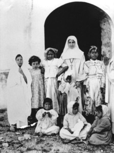 116264 Witte Zuster met Tunesische meisjes voor een kerk in Carthago