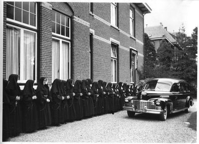 122192 Auto met het stoffelijk overschot van Mgr. J.G. van Schaik wordt (vanuit het ziekenhuis) langs de zusters bij ...