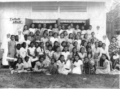 122241 Moeder Celestina en haar assistente zuster Godefrida met naaischoolleerlingen tijdens een visitatie te Medan, ...