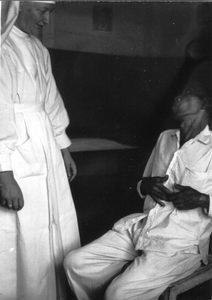 122287 Zuster Lucasina in gesprek met een patiënt in de polykliniek te Parsoburan (Noord-Sumatra), Indonesië