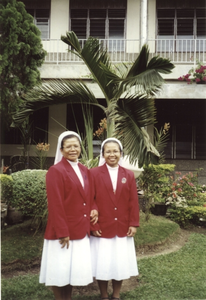 122298 Zusters Cresentia en Chrysanta in de kloostertuin met rode jasjes van het koor te Medan (Noord-Sumatra), Indonesië
