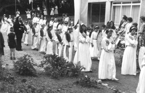 164160 Maagdengroep met op achtergrond refterzusters tijdens een sacramentsprocessie te [Heerlen/Heerenveen]