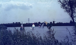 DIA00037 Surfers op de Bernisse (met de molen van Abbenbroek aan de horizon, evenals een hoogspanningsmast); ca. 1985