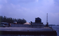 DIA69464 De zand en grindhandel bij de haven langs het Spui; ca. 1982