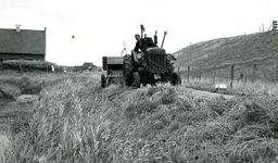 OH_ZEEDIJK_32 Een tractor met aanhanger perst het gemaaide gras langs de berm tot hooibalen; 21 juni 1959
