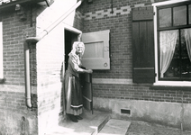 RO_DUINSTRAAT_12 Mevrouw Klok in streekdracht bij een Duinhuisje in het museum De Duinhuisjes; 1990