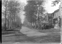 GN2235 De Stationsweg met okkerbomen, rechts een café; ca. 1925