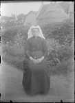 GN2877 Een vrouw met een keuvel zit in de tuin; ca. 1910