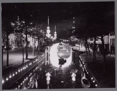 WAT001001060 Verlichte Dam en gracht bij nacht, tijdens Stadsfeest Edam. De straat links is 'het Spui'. Gracht in het ...