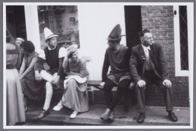 WAT001001085 Verkleedde Edammers zitten op bankjes op de stoep tijdens het Stadsfeest in Edam. Persoon uiterst rechts ...