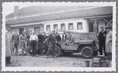 WAT001002477 Groepsportret voor een gebouw in aanbouw in Oosthuizen. Er is ook een oude jeep, stapel bakstenen en een ...