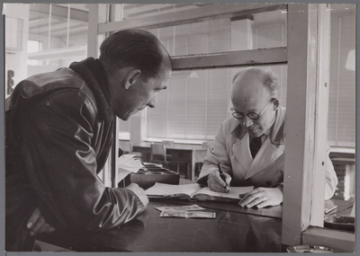 WAT001003455 Afrekenen aan de kas van de veilingvereniging B.P. en O bij de kassier de heer de Groot.