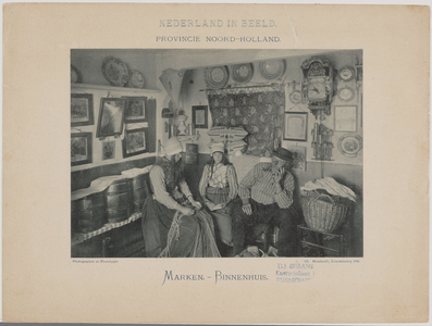 WAT001020963 Interieur van een woning op Marken. In de kamer: twee vrouwen en een man, zittend en gekleed in ...