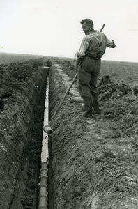 2305 - Een draineerleiding, bestaande uit korte aardewerk buizen, wordt in de sleuf gelegd