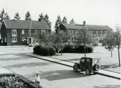 2 - Twee houten gebouwen bij een park, met een auto en een man