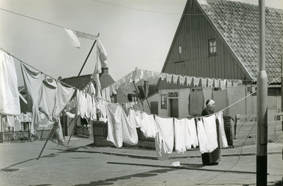 191 - Een vrouw in Urker klederdracht hangt de was op