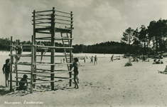 Nr.: 11901 - Zandenplas zand/strand langs water; achtergrond naaldbomen; klimtoren met spelende kinderen; zonnebadende mensen