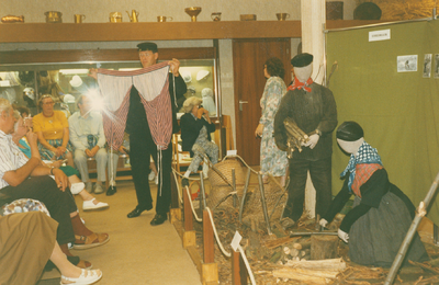 N 8131 - klederdrachtshow in de oudheidkamer; Wim Bonestroo met 'scheigordijn'; geheel rechts: Alie de Graaf; tafereel ...