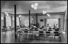 236 - grote ruimte met daarin lange tafel, met zeil gedekt, met stoelen eromheen; aan plafond ronde lampen; grote ramen ...