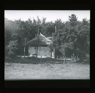  Houten schuur met daarvoor lege hooiberg tegen de bosrand