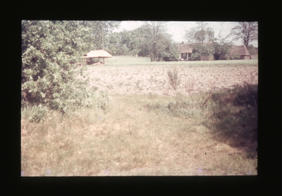  Akkerland met daarachter hooiberg leeg en boerderijtje.