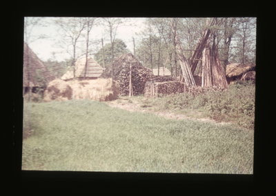  Achterkant van schuren met hooiberg en opgestapelde palen.