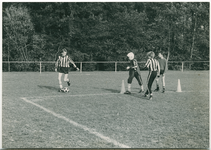 13852 - Op een veld zijn vier jongens aan het voetballen, op de lijn staan pionnen
