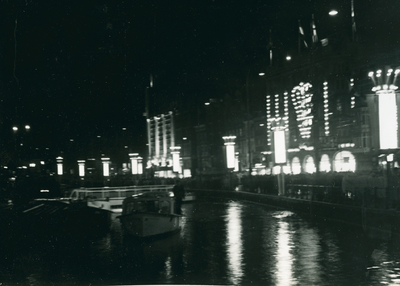 16952 - Nachtfoto van het Rokin in Amsterdam en boten in de gracht en verlichte gevels