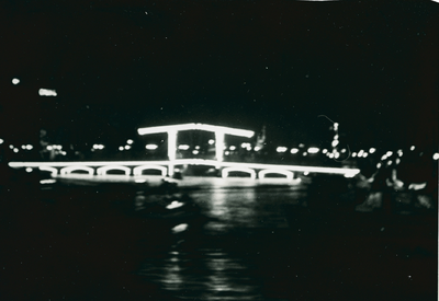 16954 - Nachtfoto van de verlichte Magere Brug over de Amstel tegenover Carré in verband met het vijftigjarig jubileum ...