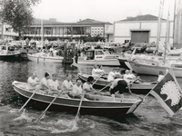 8391 - Tijdens Aaltjesdag is er een roeiwedstrijd tussen raadsleden van Harderwijk en Ermelo. Op de voorgrond de boot ...