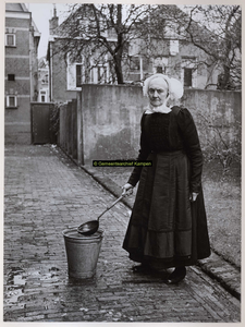 F002968 Juffrouw Beijer, J. in door-de-weekse Kamper klederdracht aan het glazenwassen.