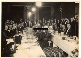 F001174 Groep genodigden tijdens een diner, rechts (zittend) burgemeester Oldenhof.