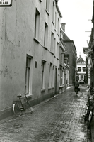 F011281 Vrouw op de fiets tijdens een regenachtige dag in de St. Jacobstraat, vroeger de Sint Jacobsteeg, dit is bij ...