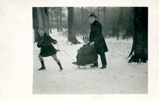 F009643 Gerie Waanders (geb. 1913) trekt de slee met Jeane Berk-Waanders (1901-1942), de slee wordt geduwd door ...