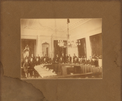 F013189 Groepsfoto van burgemeester en bestuursleden in de Raadzaal van het gemeentehuis aan de Oudestraat. De man ...