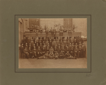 F013186 Groepsfoto van een groot aantal mannen aan de achterzijde van de Burgwalkerk, de man uiterst rechts (met ...