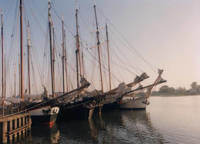 F013215 De steven en masten van vijf schepen van de bruine vloot van Kampen liggen naast elkaar aan de IJsselkade afgemeerd.