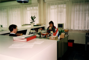 F006648 Th.M. van Mierlo (geb.1958) en Elly Christoffels (geb.1969) achter hun buro's in de studiezaal van het ...