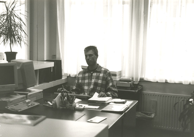 F008846 Drs. J. Mooijweer (educatie) achter zijn buro in de studiezaal van het gemeentearchief van Kampen.