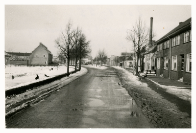 F006377 De IJsseldijk, rechts de schoorsteenpijp van de melkfabriek, links kinderen op hun sleetje al glijdend het ...